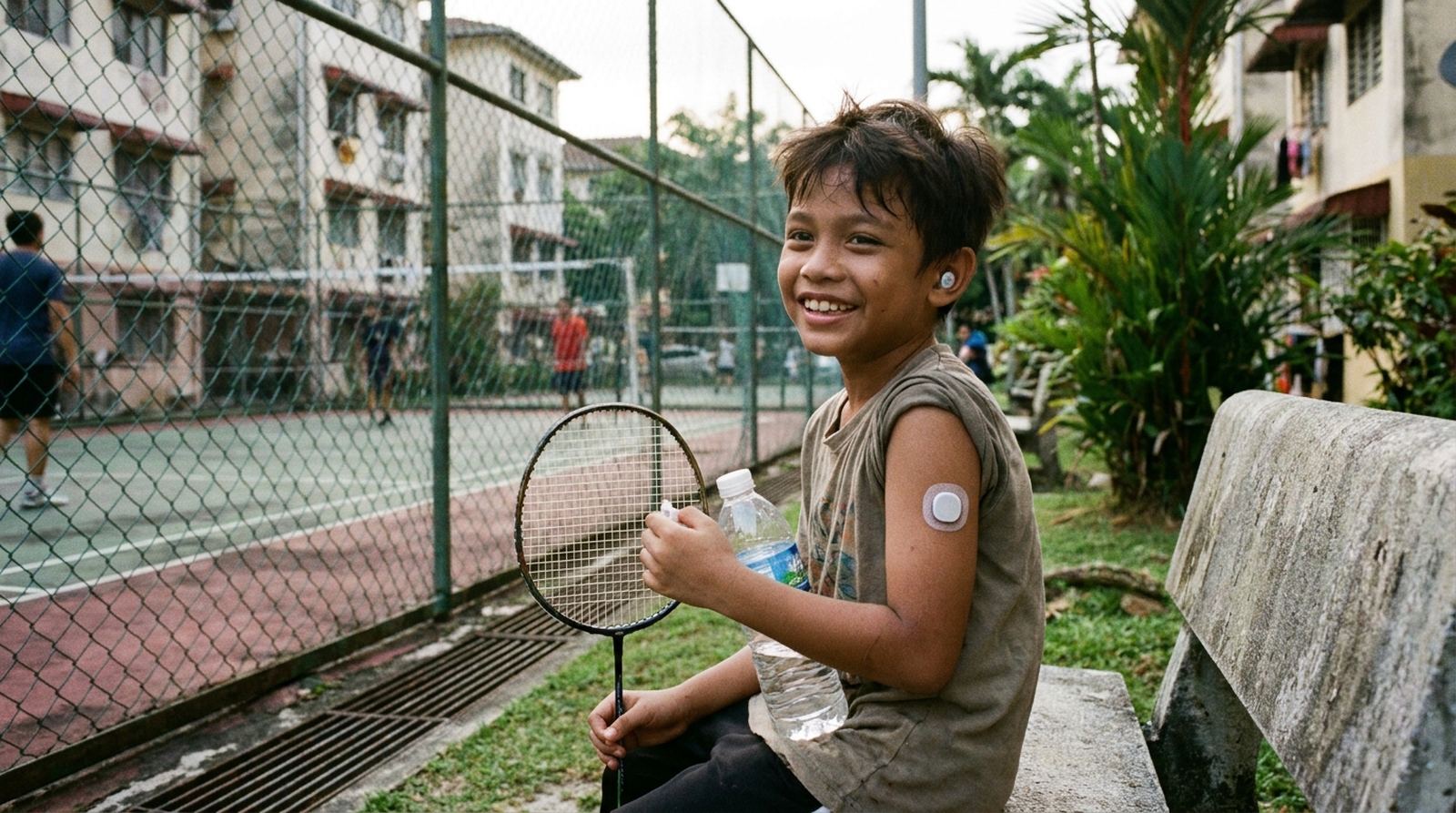 A boy resting after badminton with a glucose sensor on his arm